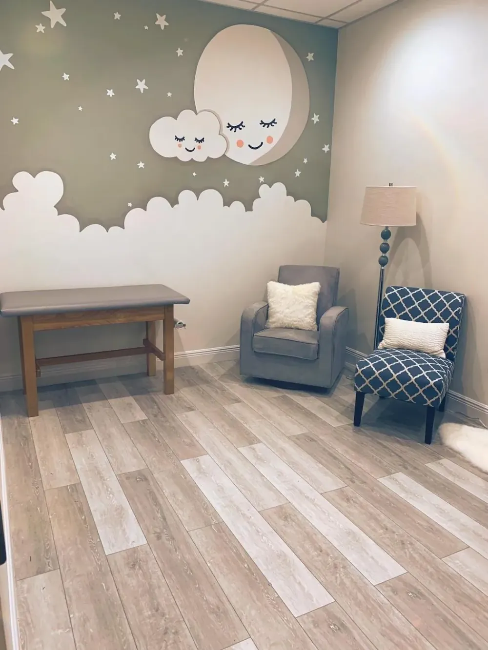 Quiet consultation room with an armchair, floor lamp, and a moon-and-stars mural.
