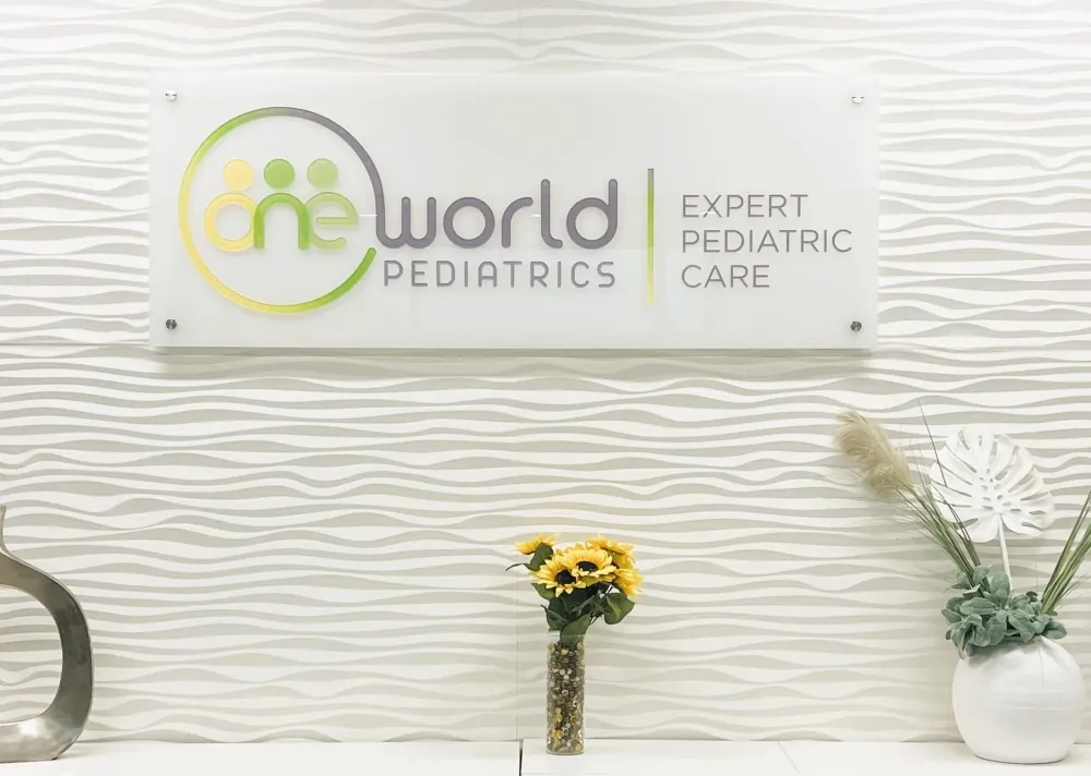 One World Pediatrics lobby sign, with the practice logo and the words Expert Pediatric Care.