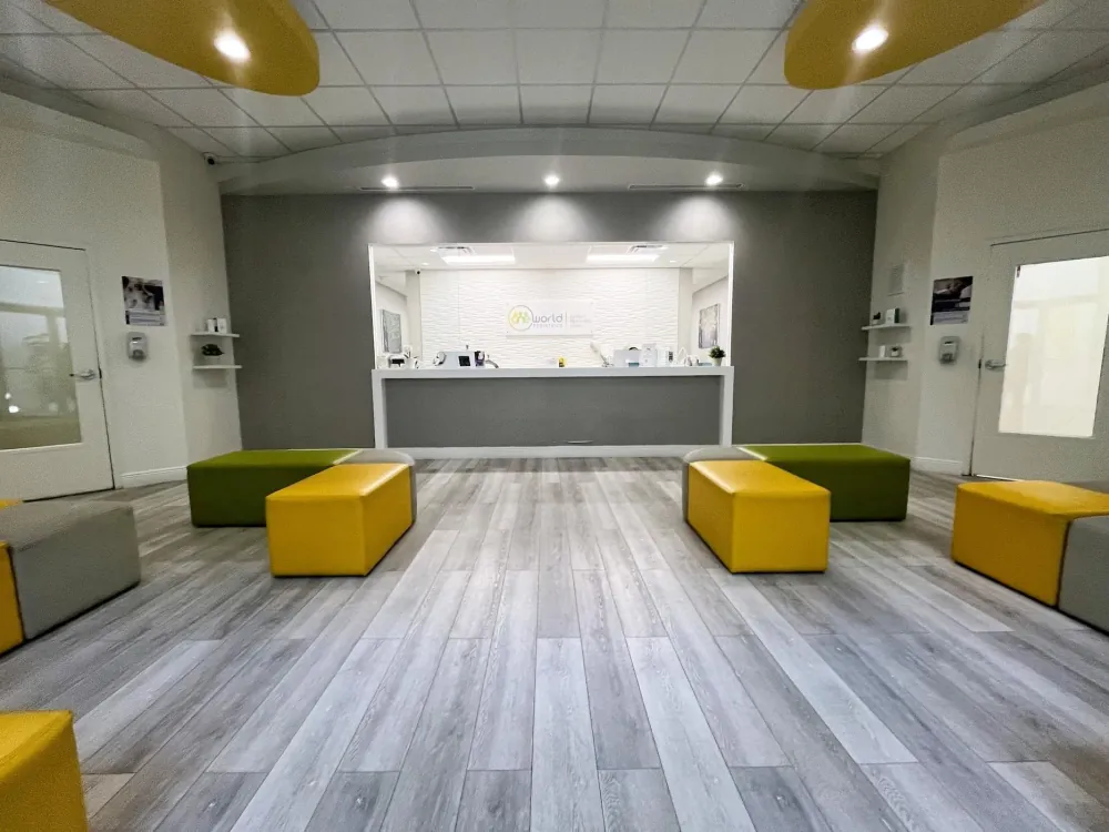 Reception area with the One World Pediatrics logo behind the front desk and colourful bench seating.