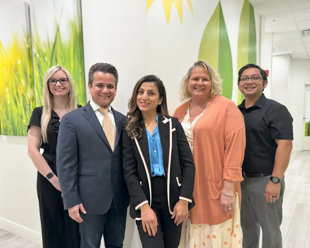 Five members of the One World Pediatrics team standing together in the office corridor.